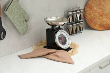 Retro mechanical kitchen scale and other utensils on white marble countertop indoors