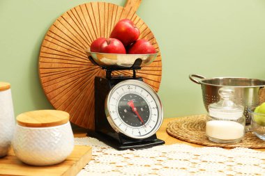 Kitchen scale, products and cooking utensils on wooden table