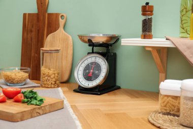 Kitchen scale, products and cooking utensils on wooden table
