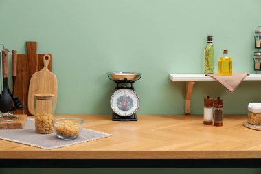 Kitchen scale, products and cooking utensils on wooden table