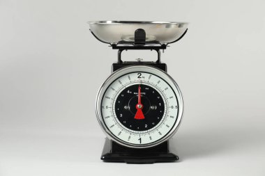 Açık gri arka planda kâsesi olan mekanik mutfak tartısı.