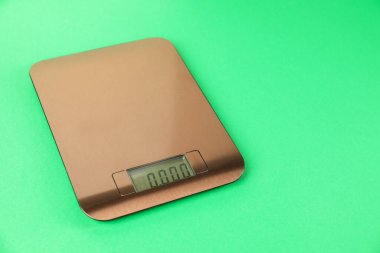 Yeşil arka planda bir elektronik mutfak terazisi. Metin için boşluk