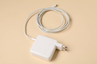 USB power adapter with charge cable on beige background, above view