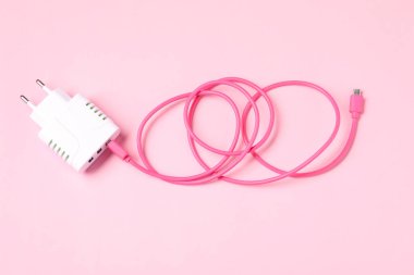 Soluk pembe arka planda şarj kablosu olan USB güç adaptörü, üst görünüm