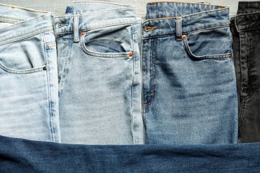 Different stylish jeans as background, top view