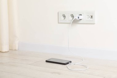 Kablolu USB adaptörü elektrik prizine takılı, akıllı telefonu içeride şarj ediyor. Metin için boşluk