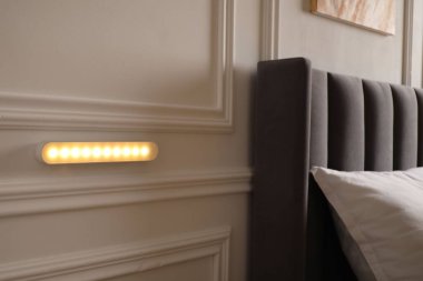 Kapalı bir odada beyaz duvarda parıldayan modern LED lamba.