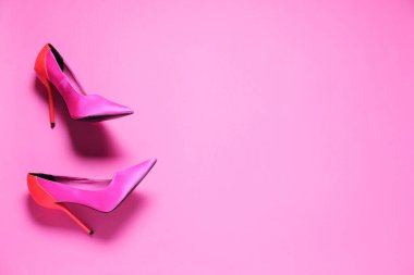 Pembe arka planda bir çift yüksek topuklu ayakkabı. Metin için boşluk