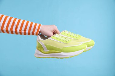 Açık mavi arka planda şık ayakkabılı kadın, yakın plan.