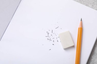 Eraser, pencil, notebook and scraps on table, top view