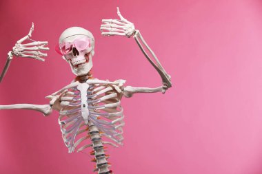 Pembe arka planda güneş gözlüklü yapay insan iskeleti modeli, metin için boşluk