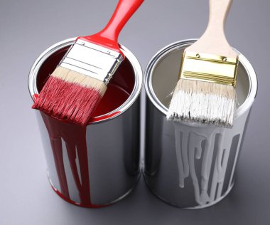 Cans of paint and brushes on grey background, closeup