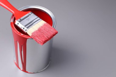 Gri arka planda kırmızı boya ve fırça kutusu, yakın plan. Metin için boşluk