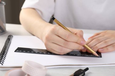 Işık masasında cetvel ve kalemle çizim yapan kadın, yakın plan.