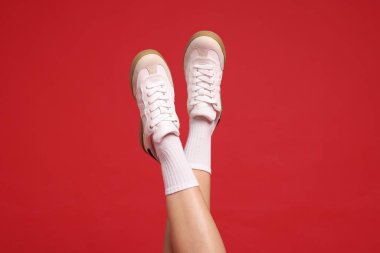 Kırmızı arka planda şık ayakkabılar giyen kadın, yakın plan.