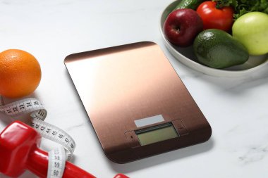 Elektronik mutfak ölçeği, mezura, dambıl ve beyaz mermer masa üzerindeki ürünler, yakın çekim. Diyet