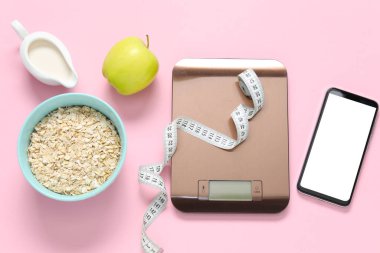 Elektronik mutfak ölçeği, mezura, akıllı telefon ve pembe arka plandaki ürünler, düz yatak. Diyet
