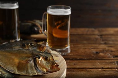 Kurutulmuş balık ve bira bardakları ahşap masada, yakın plan. Metin için boşluk