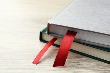 Açık ahşap masa üzerinde kırmızı kurdele yer imleri olan kitaplar, yakın plan. Metin için boşluk
