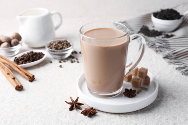 Cam bardakta Aromatik Masala çayı, baharatlar ve esmer şeker beyaz desenli masa üzerinde