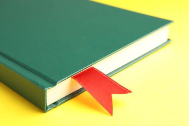 Sarı arkaplanda kırmızı kurdele yer imi olan kitap, yakın plan