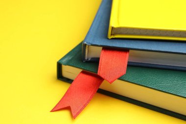 Sarı arkaplanda kırmızı kurdele yer imlerine sahip kitaplar, yakın plan