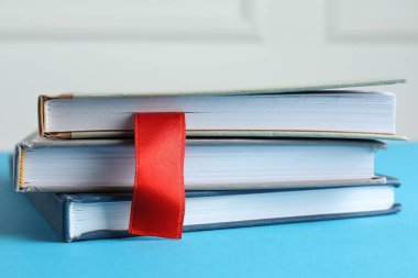 Kırmızı kurdele yer imi ve mavi masadaki renkli kitaplarla ışık arkaplanı, yakın plan