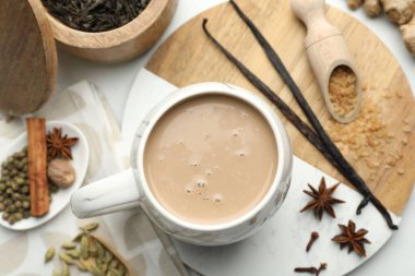 Fincanda Aromatik Masala çayı, beyaz masada kahverengi şeker ve baharatlar, düz uzanmış