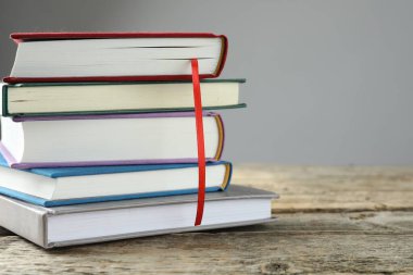 Kırmızı kurdele ayıracı ve renkli kitaplarla dolu bir kitap. Gri arka planda, yakın planda. Metin için boşluk