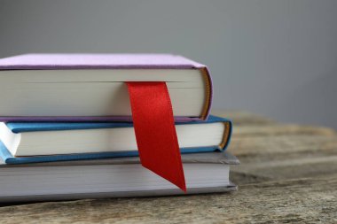 Kırmızı kurdele yer imi ve ahşap masadaki renkli kitap gri arkaplanda, yakın plan