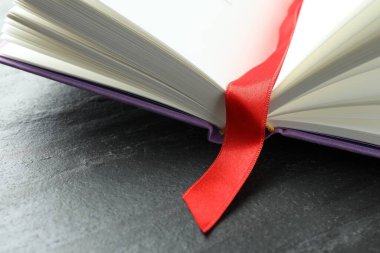 Koyu dokulu masa üzerinde kırmızı kurdele yer imi olan kitabı aç, kapat