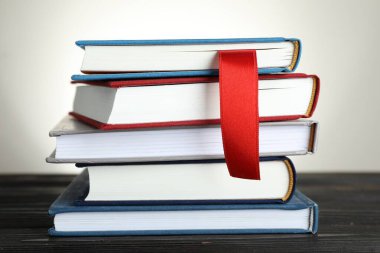 Açık gri arkaplan, yakın plan, ahşap masa üzerinde kırmızı kurdele yer imi ve renkli olanlar kitap