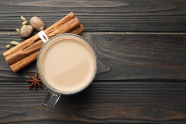 Cam bardakta Aromatik Masala çayı ve ahşap masada baharatlar, düz yatak. Metin için boşluk