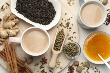 Açık gri masada fincanlarda, baharatlarda, kuru yapraklarda ve balda Aromatik Masala çayı.