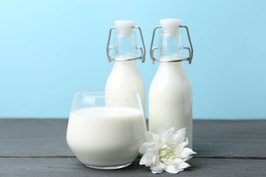 Taze süt ve çiçek ahşap masada açık mavi arka planda