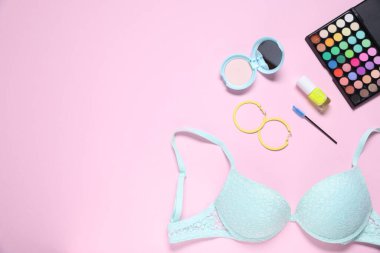 Düz kompozisyon, dantel sütyen ve kozmetik ürünler pembe arka planda. Metin için boşluk