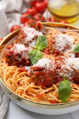 Köfteli lezzetli makarna, peynir ve fesleğen beyaz masada, yakın plan.