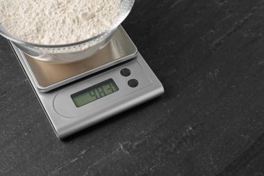 Elektronik mutfak terazisi ve koyu dokulu bir kase un. Metin için boşluk