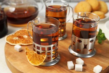 Beyaz ahşap masada servis edilen metal tutacaklı çay bardakları.