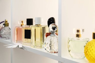 Dükkandaki raflarda farklı parfüm şişeleri ve parfümler var.