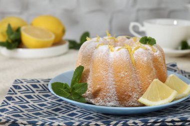 Limon aromalı lezzetli pasta, pudra şekeri ve açık dokulu masa üzerinde nane şekeri, yakın plan.