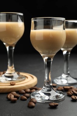 Bardakta kremalı kahve likörü ve siyah masada fasulye, yakın plan.