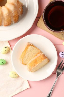 Lezzetli kek parçaları, pembe ahşap masada paskalya yumurtası ve çay, düz uzanma.