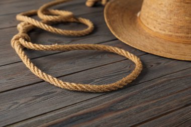 Pamuk ipten ve ahşap arka planda hasır şapkadan yapılmış kement, yakın plan.