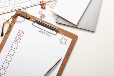 İşaretli kutular, kırtasiye malzemeleri, bardaklar ve bilgisayar klavyesi olan kontrol listesi beyaz masada, düz konumda. Metin için boşluk