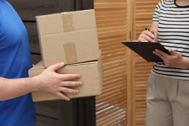 Kutuları ve alıcıları olan kurye kapalı alanlarda paket teslimatı için imzalıyor.