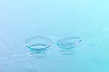 Kontakt lensler ve su damlaları mavi ayna yüzeyine, yakın plan.