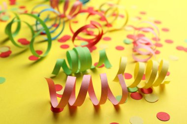 Sarı arka planda renkli yılan desenleri ve konfeti.