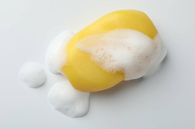 Beyaz arka planda köpük olan sabun çubuğu, üst görünüm