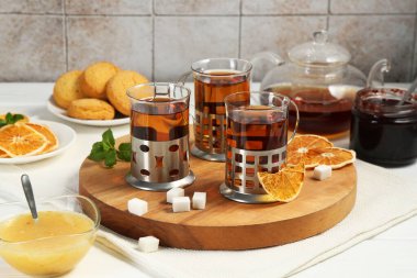 Beyaz ahşap masada servis edilen metal tutacaklı çay bardakları